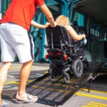 Woman in a powered wheel chair using ramp to access the back of her transport van
