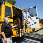 A man standing on wheelchair lift leaving a school bus